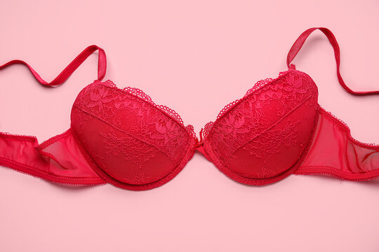 Red female bra on pink background, closeup