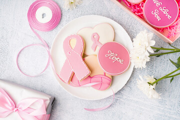 Plate with pink cookies in shape of ribbon on grey grunge background. Breast cancer awareness concept