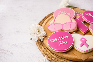 Obraz na płótnie Canvas Cookies with pink ribbons and supportive words on white grunge background. Breast cancer awareness concept