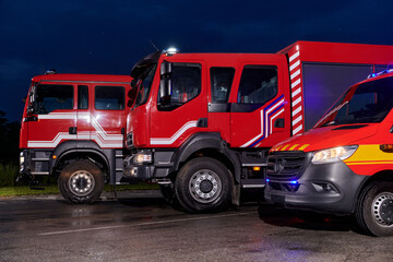 A pair of highly modern and quality fire trucks illuminate the night with their rotating lights,...