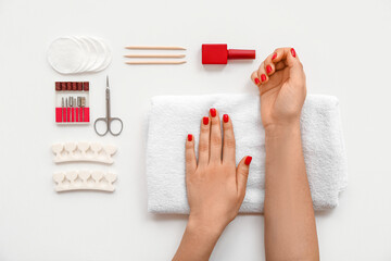 Female hands with stylish red nails and manicure equipment on white background