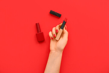 Female hand with stylish red manicure holding lipstick and nail polish bottle on color background