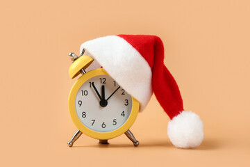 Alarm clock with Santa hat on color background