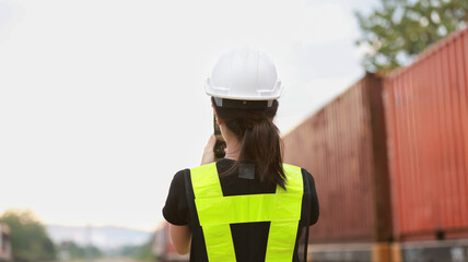 Young woman wearing safety vest check cargo container at train station
