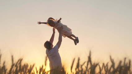 Dad plays with his daughter, throws up child with his hands in sky, outdoors. Family game concept. Childish, superhero, fly.Happy Father, child, little girl have fun together in park against sun - obrazy, fototapety, plakaty