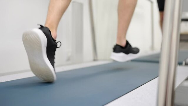Close-up video of the rear view of the legs of a man running on a treadmill during a cardiac stress test