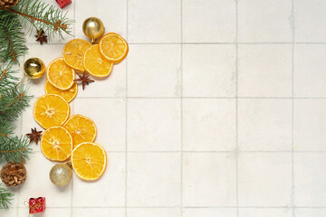 Dried orange slices with fir branches, star anise and Christmas balls on white tile background