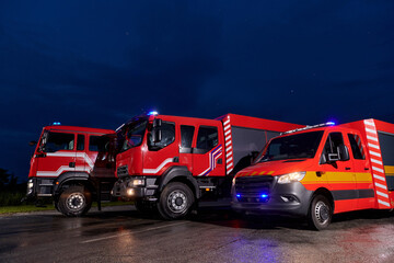A pair of highly modern and quality fire trucks illuminate the night with their rotating lights,...