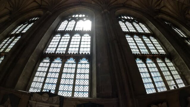 LOW ANGLE VIEW: Bright rays of sunlight shine through the magnificent window. Beautiful architectural details in every corner of the Canterbury Cathedral. Stunning religious and historical monument.
