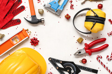 Frame made of construction tools and Christmas decorations on light background