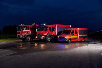 A pair of highly modern and quality fire trucks illuminate the night with their rotating lights,...