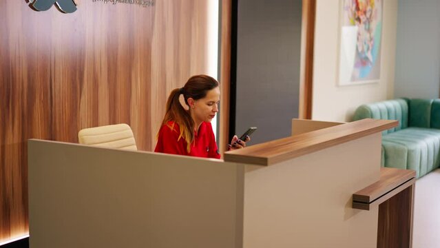 A girl administrator of a medical center sits at the reception and makes appointment for patients to see doctor by phone
