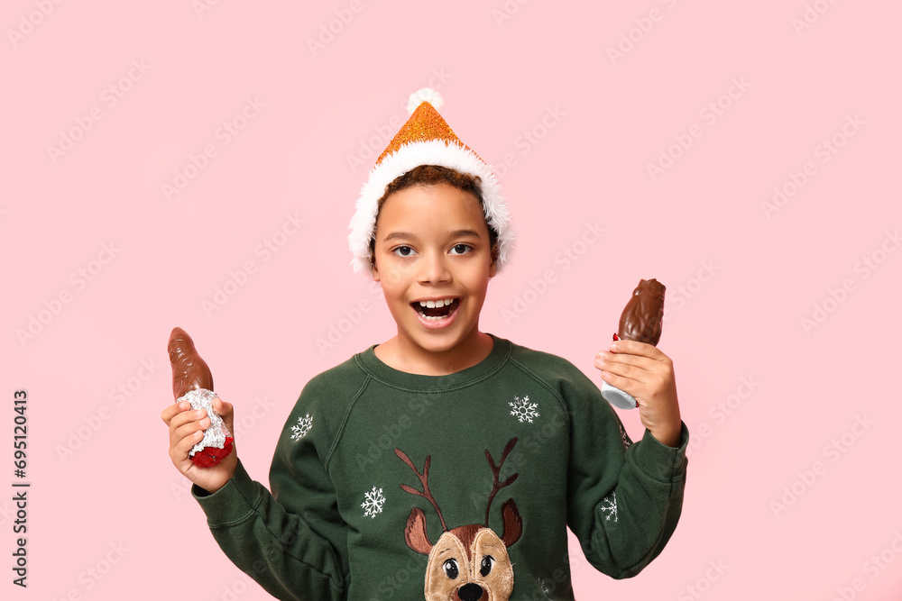 Poster cute little african-american boy with chocolate santa claus on pink background