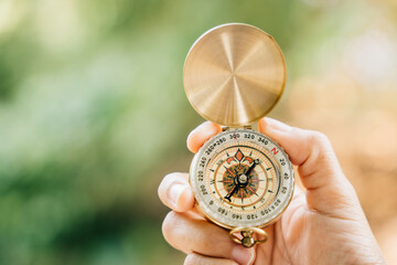 A close-up of a hand clutching a compass in the heart of a green forest. This image leaves space for text and signifies travel lifestyle and the strategic management of a thriving business.