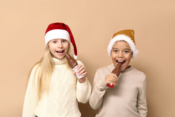 Cute little children eating chocolate Santa Claus on brown background