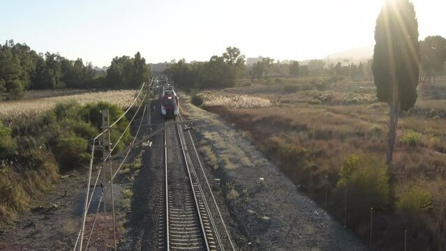 Passenger train approaching and passing at sunset