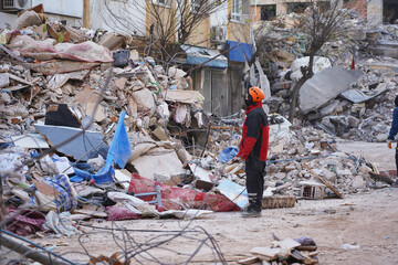 A rescue team is standing in front of a building site destroyed by a large earthquake to evacuate...