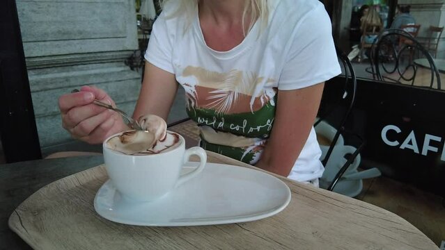 Woman tourist drinking cappuccino breakfast in a coffee shop of Switzerland, Ticino Canton.
