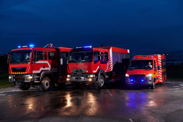 A pair of highly modern and quality fire trucks illuminate the night with their rotating lights, symbolizing the cutting-edge technology and preparedness of the firefighting fleet, ready to respond to