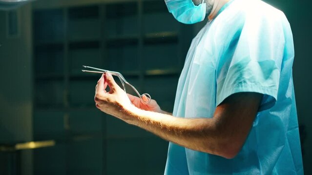 Close-up shot of a doctor surgeon in a special uniform preparing instruments before surgery in operating room