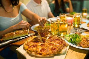 Close up of friends eating delicious pizza at night