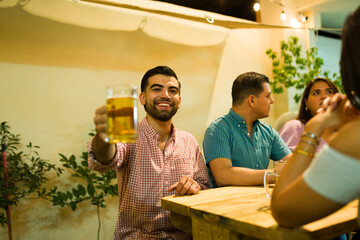 Excited man making a toast drinking beer with friends