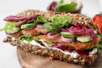 Delicious sandwich with schnitzel on wooden board, closeup