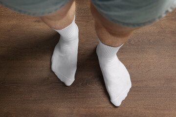 Man in stylish white socks standing on wooden floor, top view