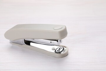 Beige stapler with staples on light wooden table, space for text
