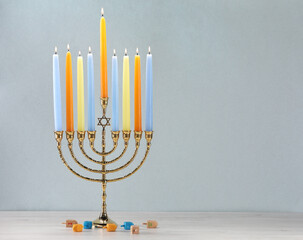Hanukkah celebration. Menorah with burning candles and dreidels on wooden table against white background, closeup. Space for text