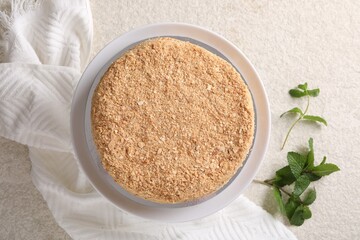 Delicious Napoleon cake and mint on beige table, flat lay