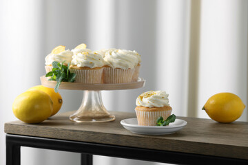 Delicious lemon cupcakes with white cream, mint and lemons on wooden table