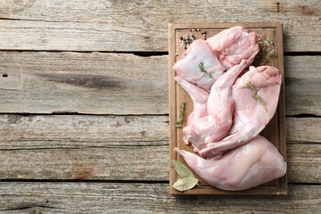 Fresh raw rabbit meat and spices on wooden table, top view. Space for text