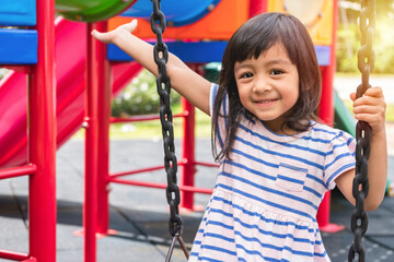 Fototapeta na wymiar Kid play at school or kindergarten yard. Kid on colorful swing. Child playing outdoor playground.