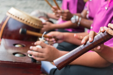 Boys playing Thai musical instrument close up on oboe. 