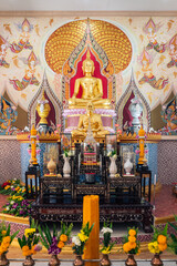 Beautiful buddha statue worship with flowers, incense sticks, candles in chapel, Thai temple.