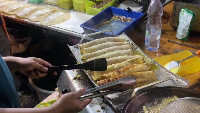 Indonesian street food chef is preparing Turkish kebabs. Partial scenes capture the cook busy at work, and the surrounding atmosphere reflects the ongoing evening at a bazaar event.