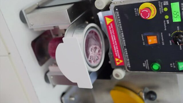Placing the bubble tea in the sealing machine. Vertical video.