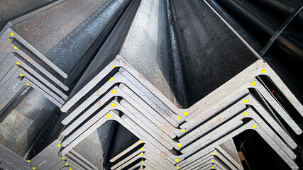 Stacks of angle iron in a factory on shelves in a warehouse Metal profile corners in packs Equal angle steel, angle steel, metal profile angles in packs at the metal products warehouse. - obrazy, fototapety, plakaty