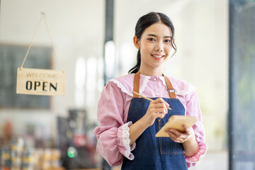 Portrait of happy waitress standing at restaurant entrance. SME entrepreneur young business asian...