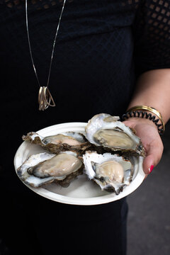 Woman holding plate of raw oysters