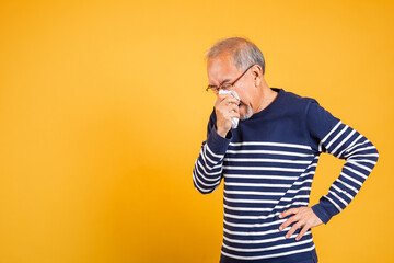 Pensioner unwell. Asian older man cold having flu and sneezing from sickness virus problem use...