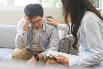 Fotobehang Psychology, depression. Sad, suffering asian young man, male consulting with psychologist, psychiatrist while patient counseling mental problem with doctor at clinic. Encouraging, therapy, health care © KMPZZZ
