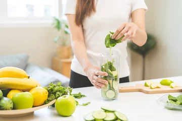 Foto op Plexiglas Vegetable smoothie detox, woman hand making healthy raw fresh green fruit juice with blender machine, preparing drink with spinach in kitchen at home, eating vegan diet. Healthy dieting, weight loss. © KMPZZZ