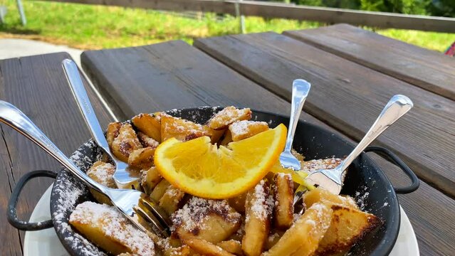 Traditional Austrian Kaiserschmarren dessert with a stunning mountain view in Tyrol Austria, sweet fluffy shredded pancake with an orange in Serfaus Fiss Ladis, summertime, 4K shot