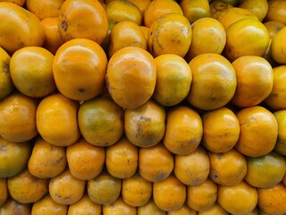 Close up pile of tasty fresh oranges sold at the market as a background.
