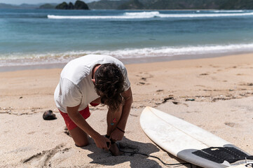 Surfer tying the leash of shortboard before surfing, Indonesia, Asia