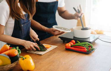 Happy asia young couple cooking together with vegetables with Bread and fruit in cozy on wooden kitchen table, love . - obrazy, fototapety, plakaty