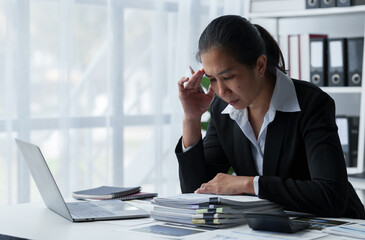 Tired Asian business woman Stress from paperwork, headaches, sleepiness, boredom from sitting at a...