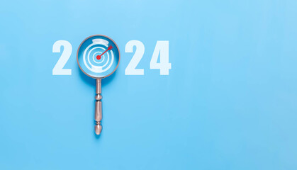 magnifying glass shows the new year 2024. concept of action business plan targets, and growth. The...